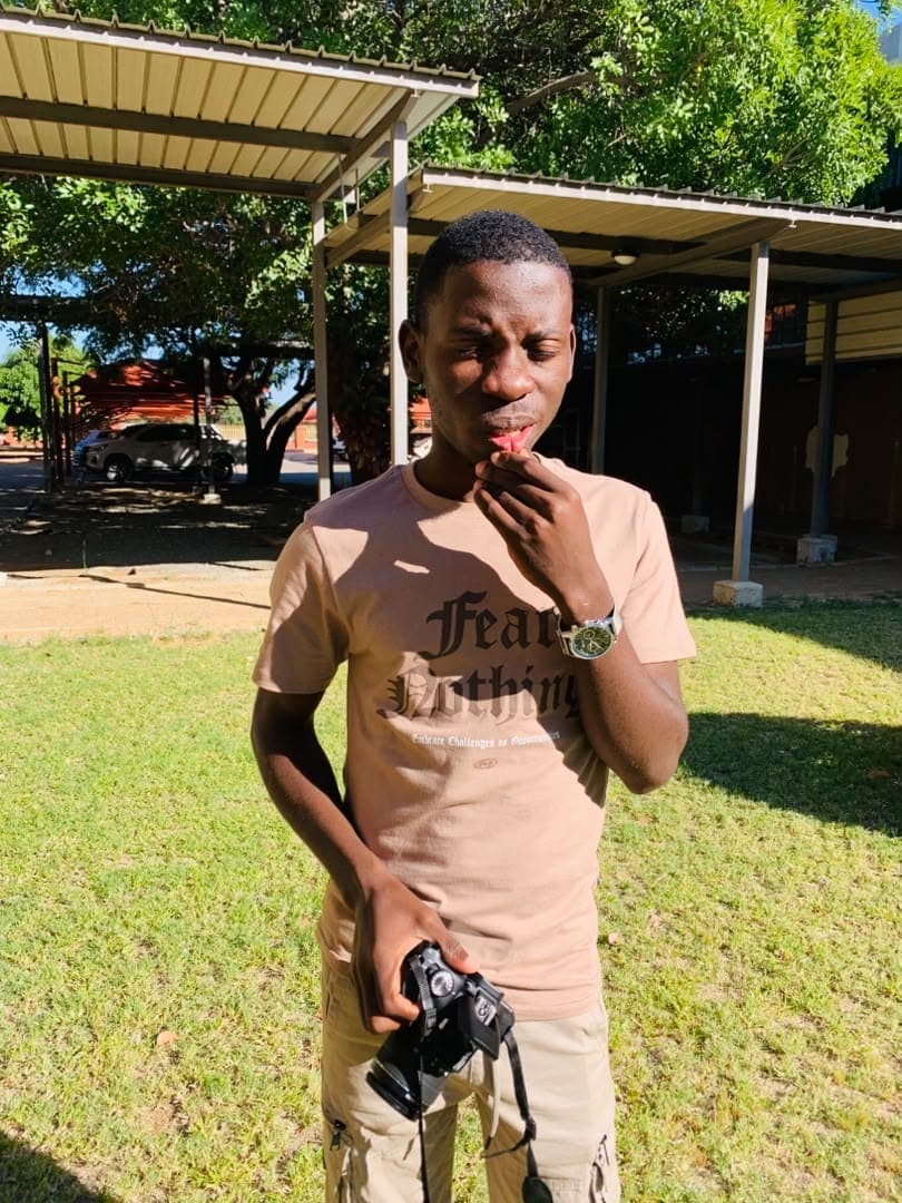 Kudumo Kupembona Andreas in a candid outdoor photograph with a camera